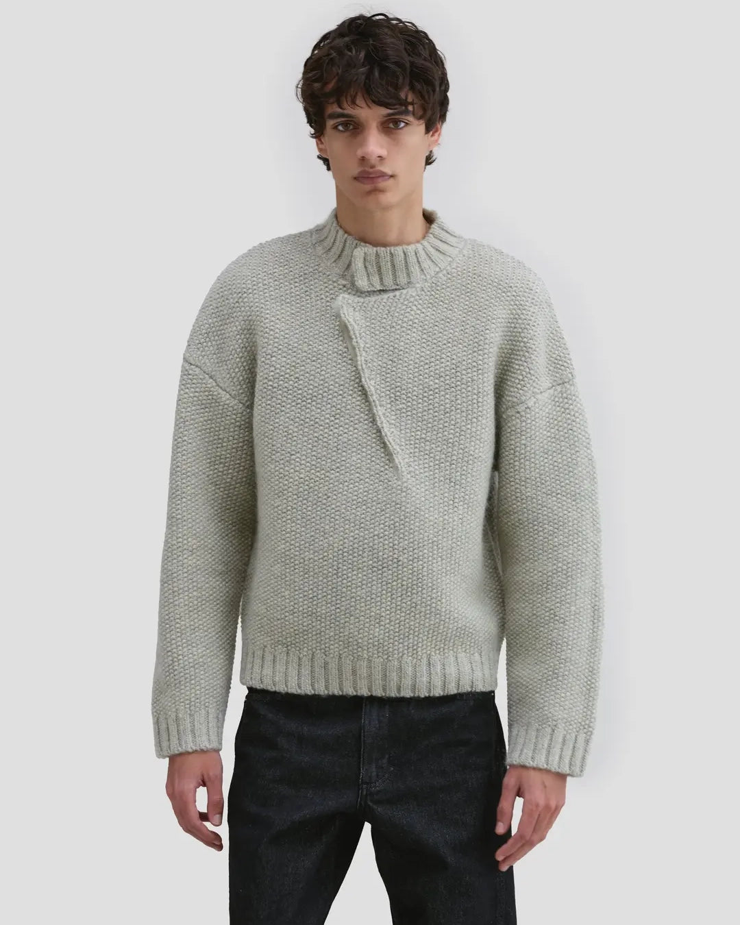 Model wearing Eckhaus Latta Roving Pullover in dove with a relaxed fit and asymmetrical Henley collar.