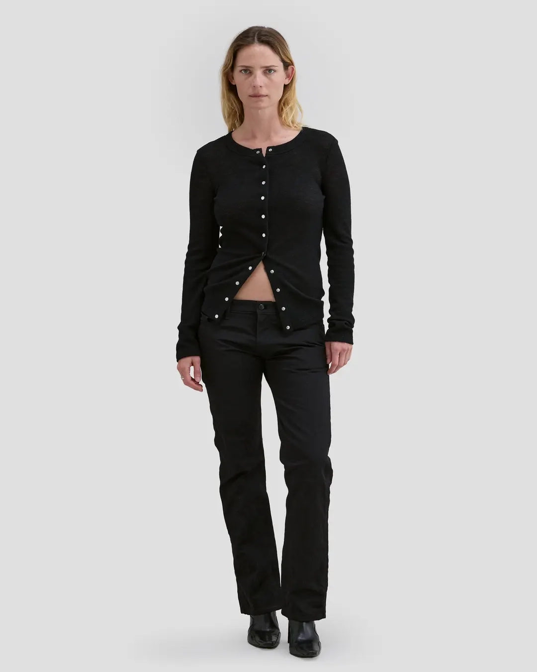 Model wearing Eckhaus Latta Scrunch Cardigan in black with a slim fit and nickel snap closures.