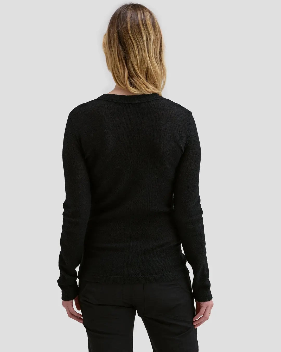 Back view of model wearing Eckhaus Latta Scrunch Cardigan in black with a slim fit and nickel snap closures.