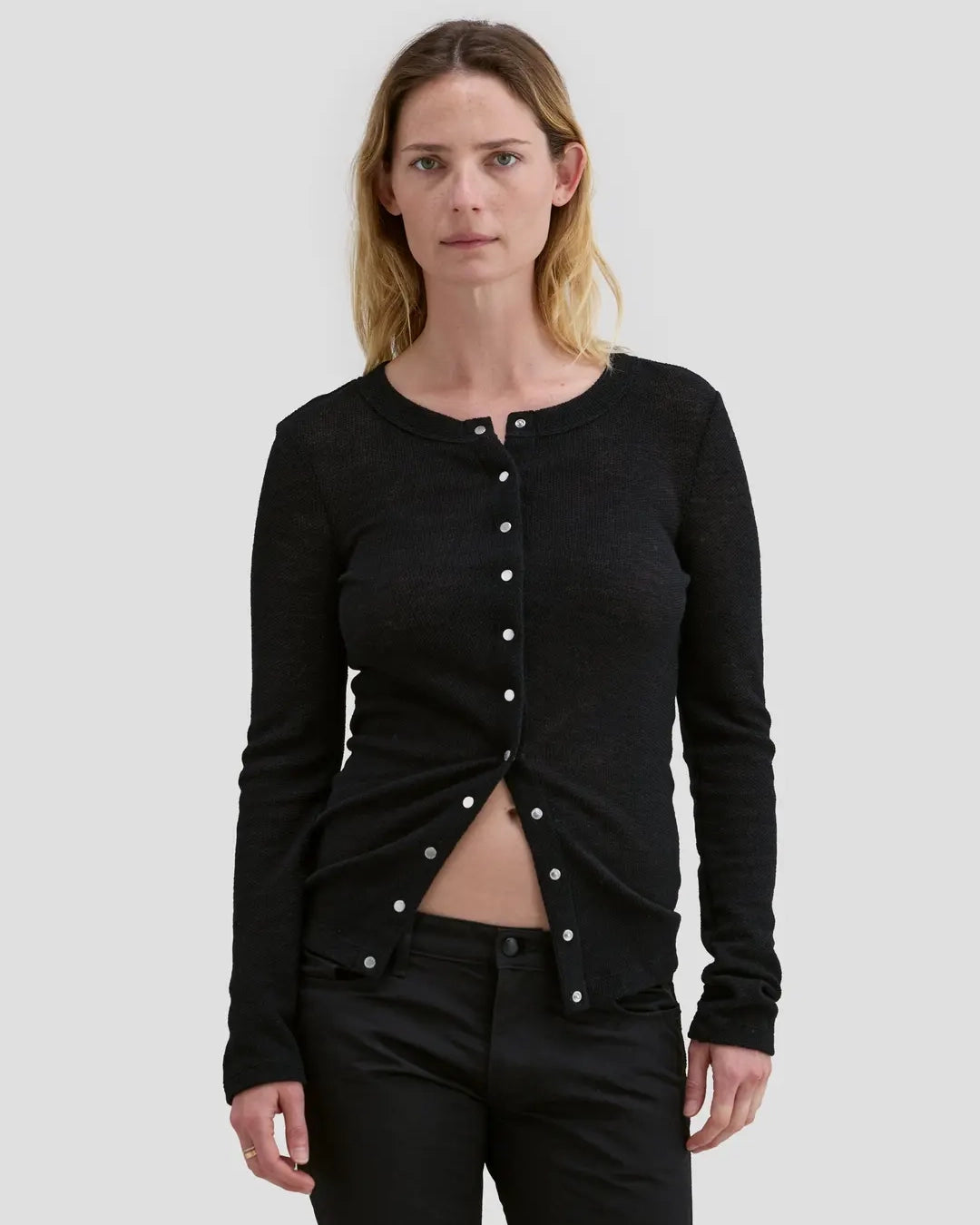 Model wearing Eckhaus Latta Scrunch Cardigan in black with a slim fit and nickel snap closures.