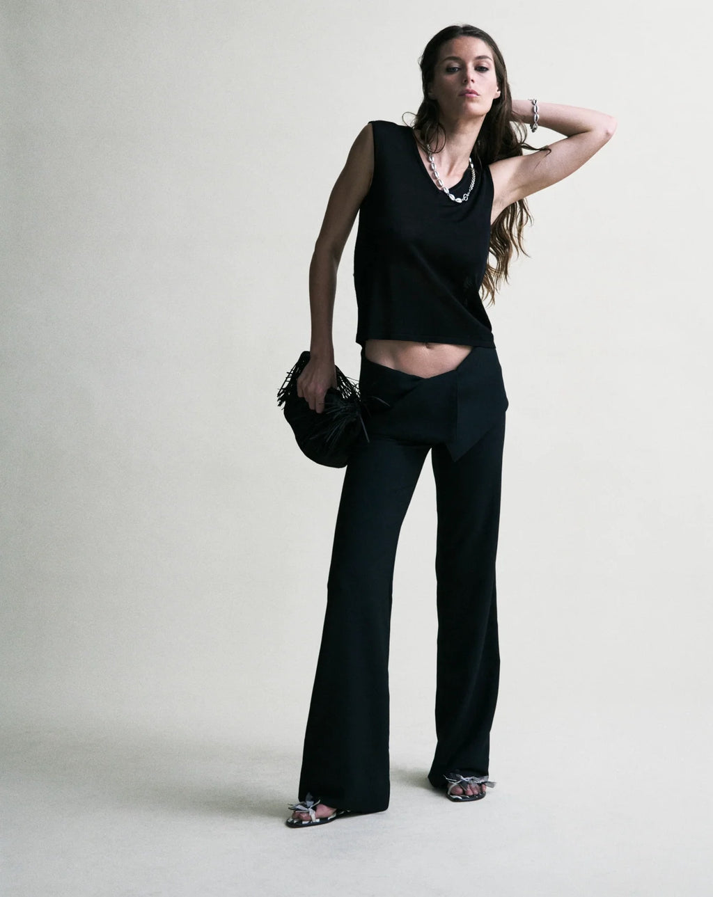 Woman wearing a black sleeveless top and black pants against a white background