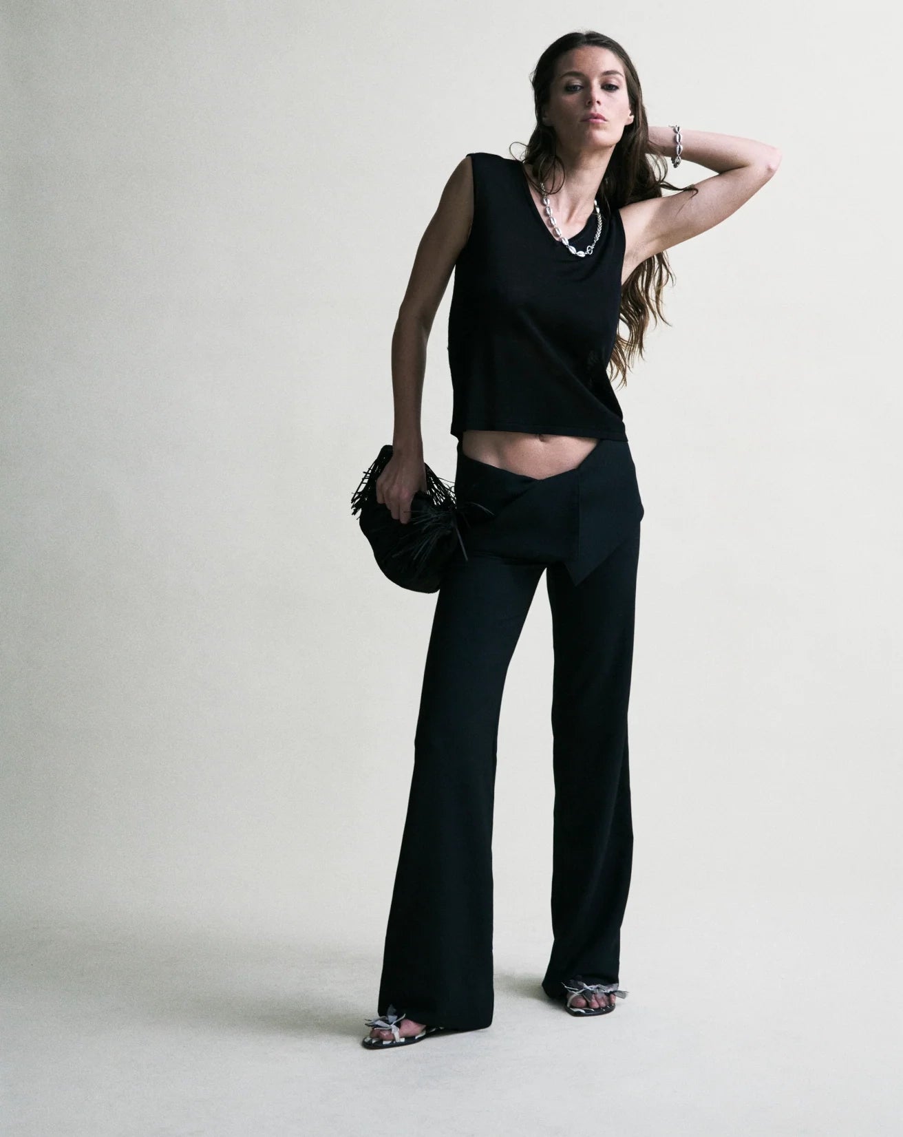 Woman wearing a black sleeveless top and black pants against a white background