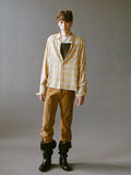 Person wearing a plaid shirt, brown pants, and black boots against a gray background