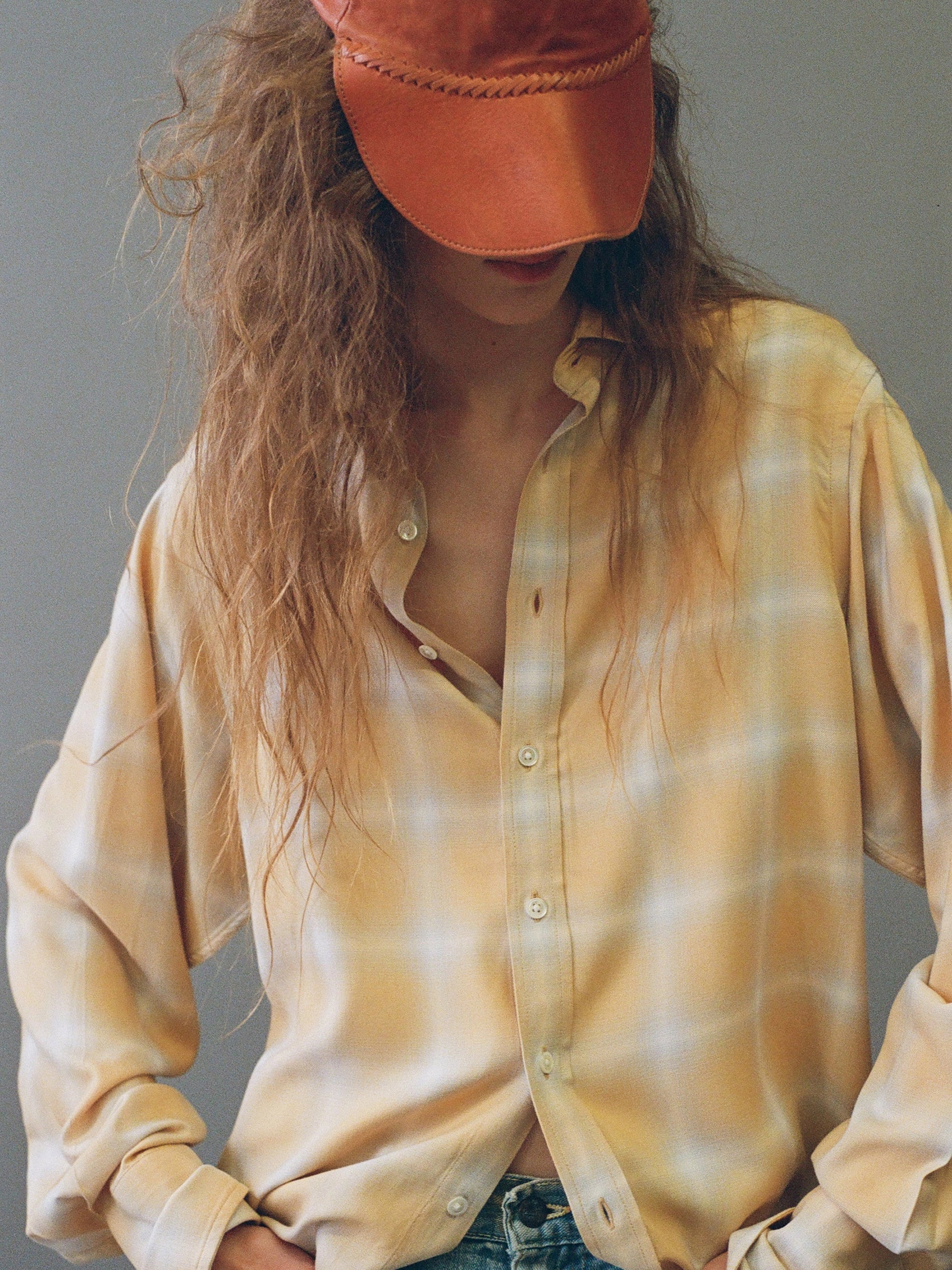 Close-up of model wearing EMILY DAWN LONG Jeff's Shirt in Japan Plaid and an orange cap.