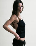 Woman wearing a black tank top against a plain background