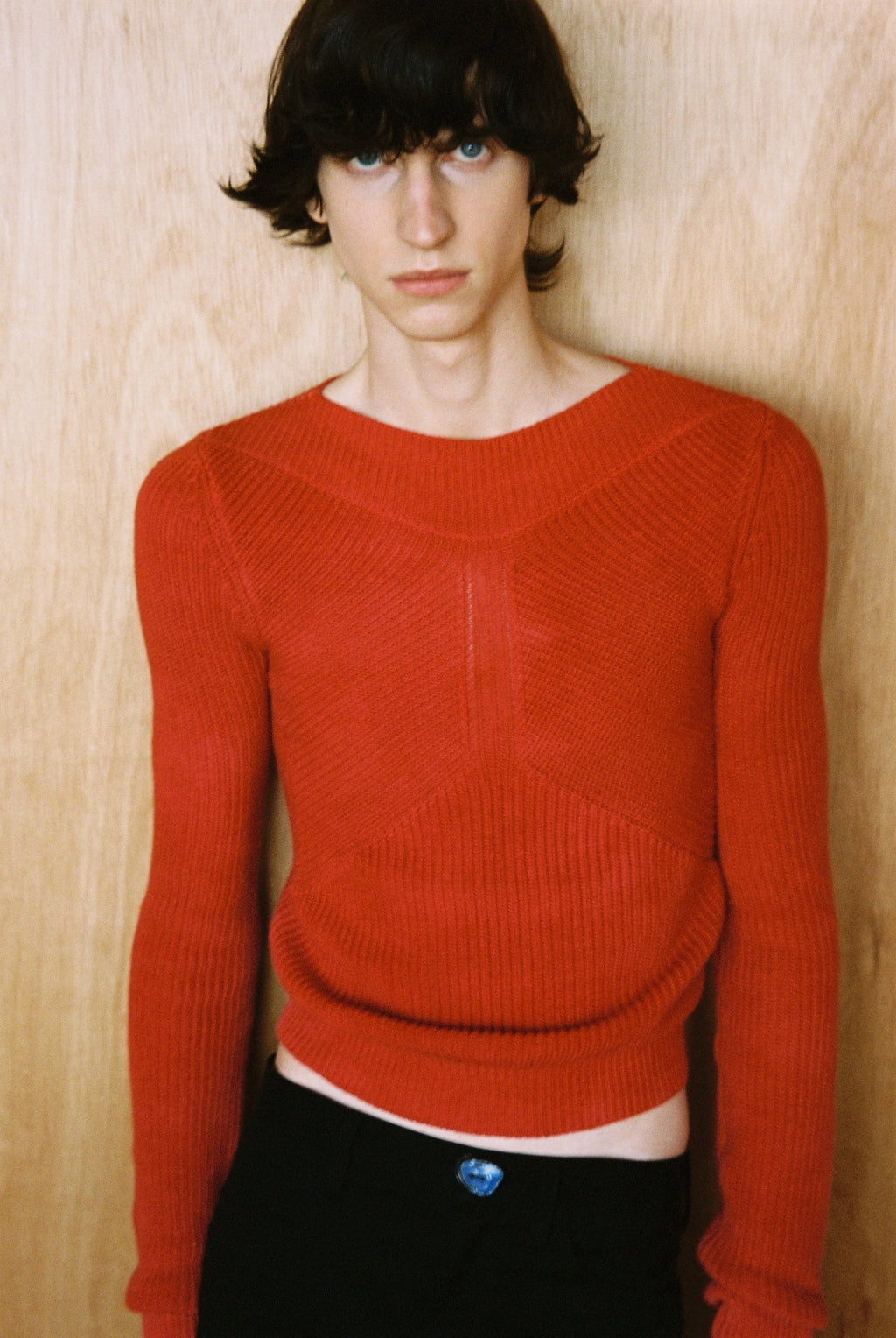 Person wearing a red sweater against a wooden background