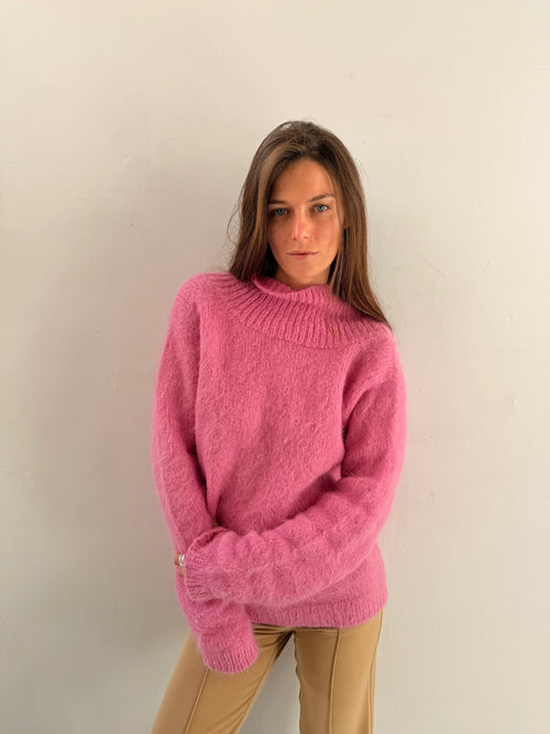 Woman wearing a pink sweater against a plain background