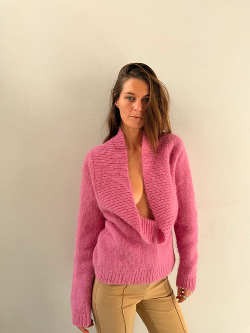 Woman wearing a pink sweater against a plain background
