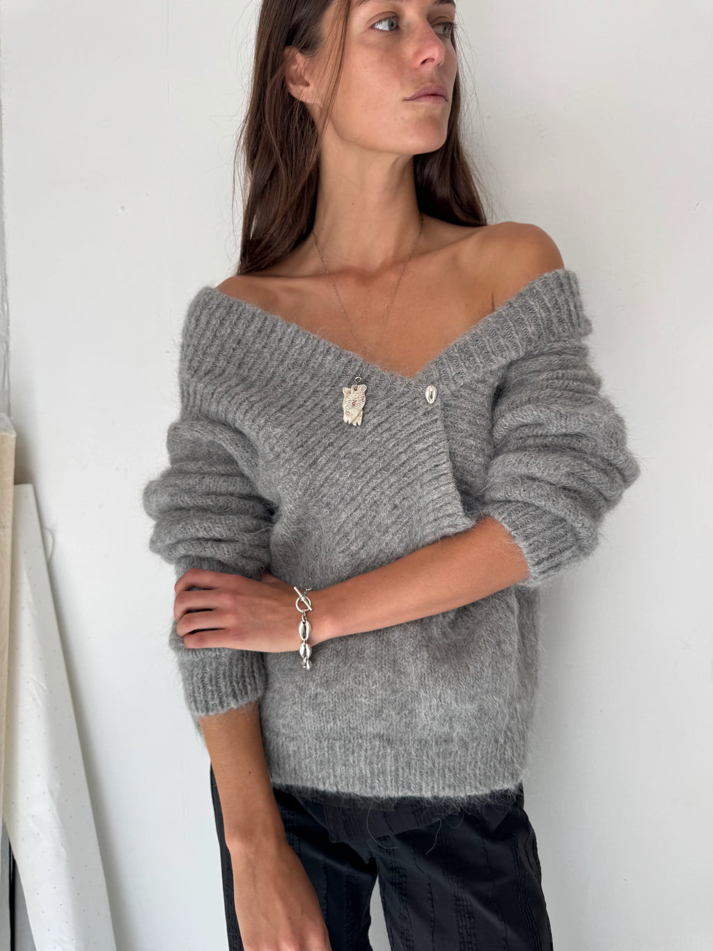 Woman wearing a gray off-shoulder sweater against a white background