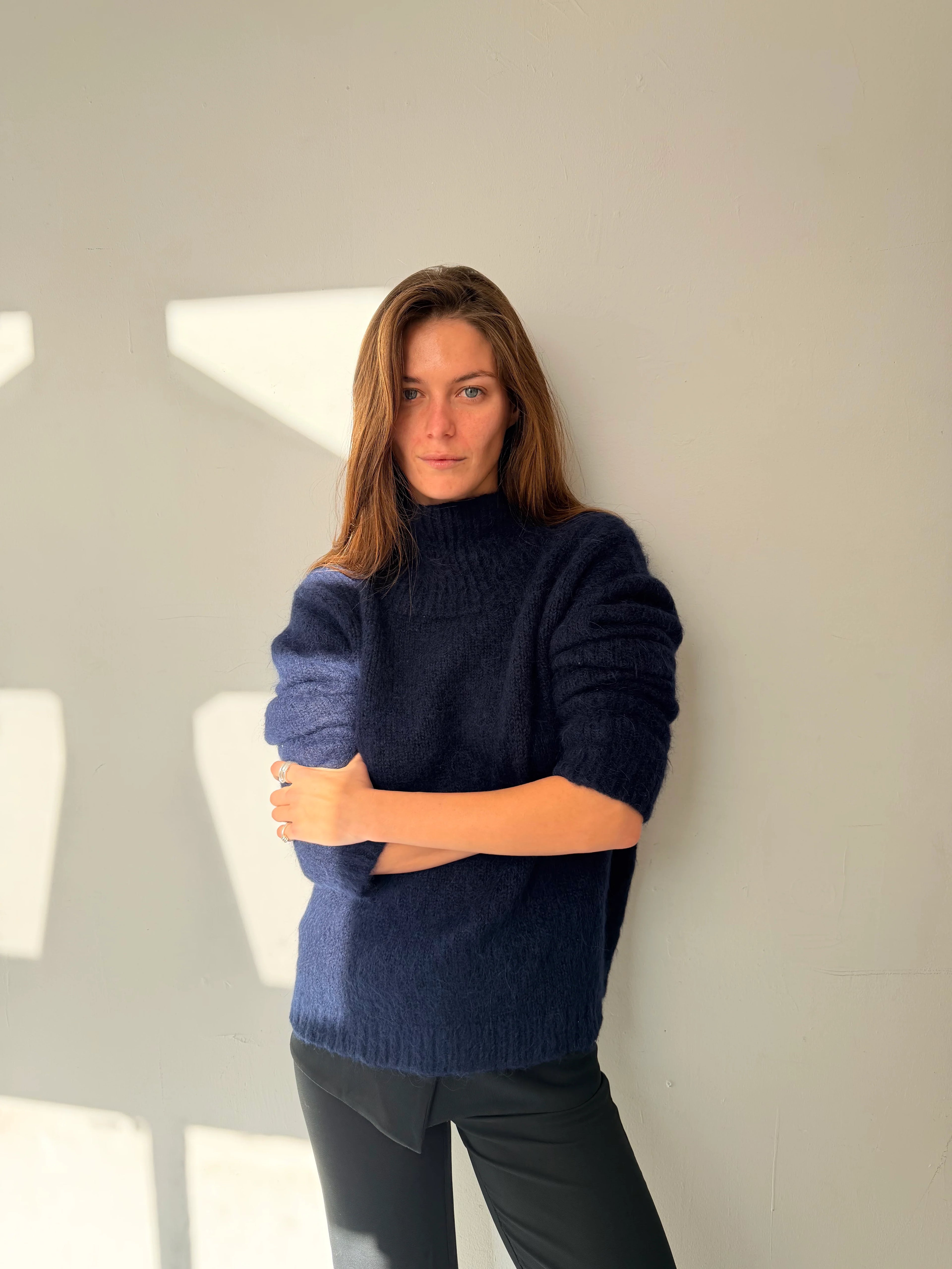Woman wearing a dark blue sweater against a light background