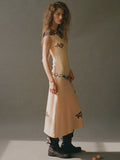 Woman wearing a beige dress with black patterns on a plain background