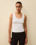 Model wearing Hillie Tank in White by FLORE FLORE, a fitted tank in organic cotton jersey with a scoop neckline.