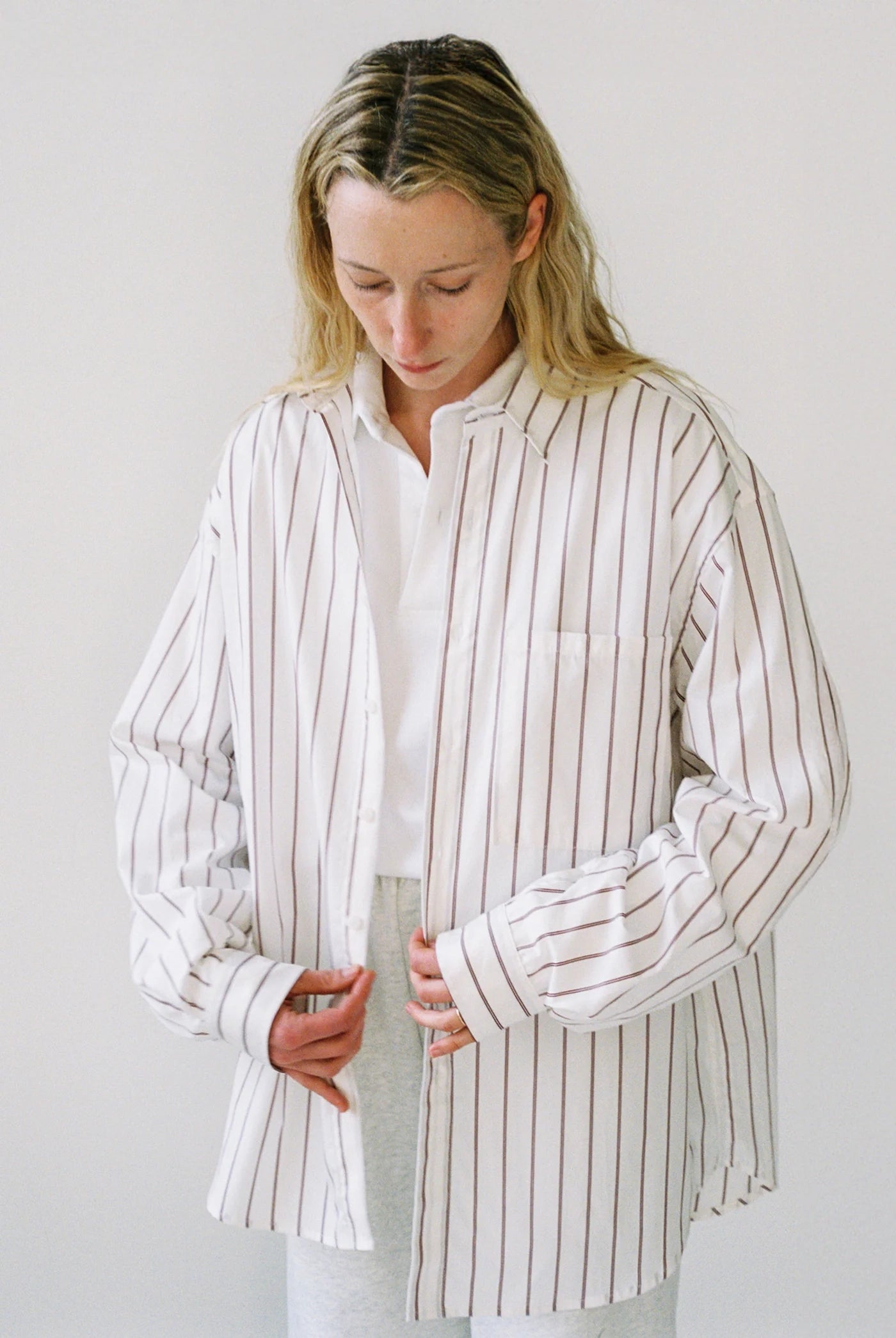 Woman wearing a white shirt with black vertical stripes against a plain background
