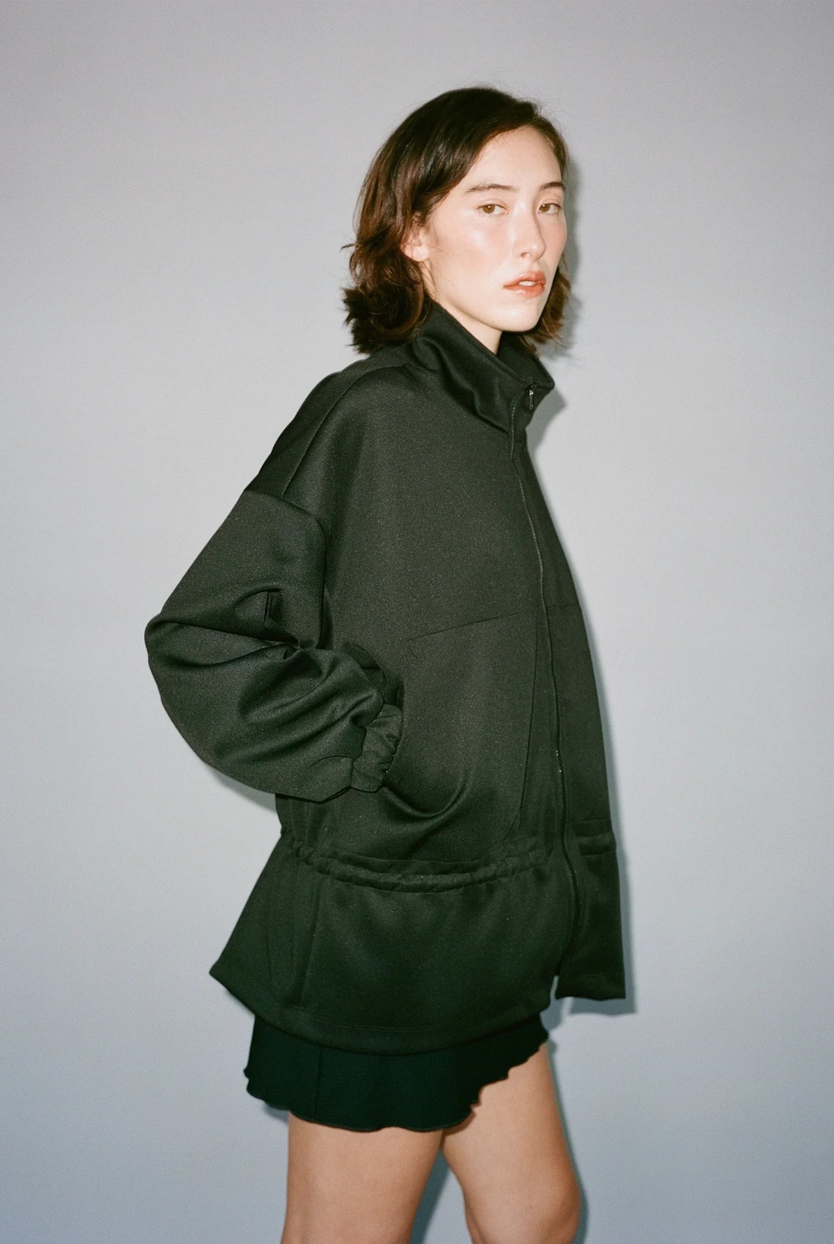 Person wearing a dark green outfit against a plain background