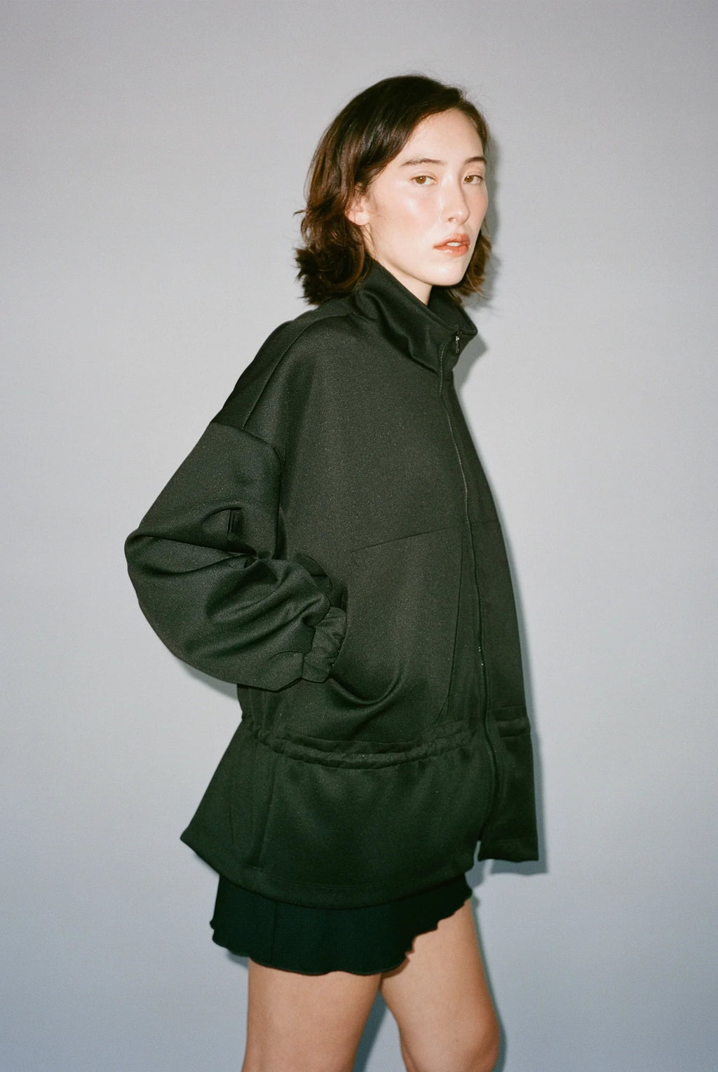 Person wearing a dark green outfit against a plain background