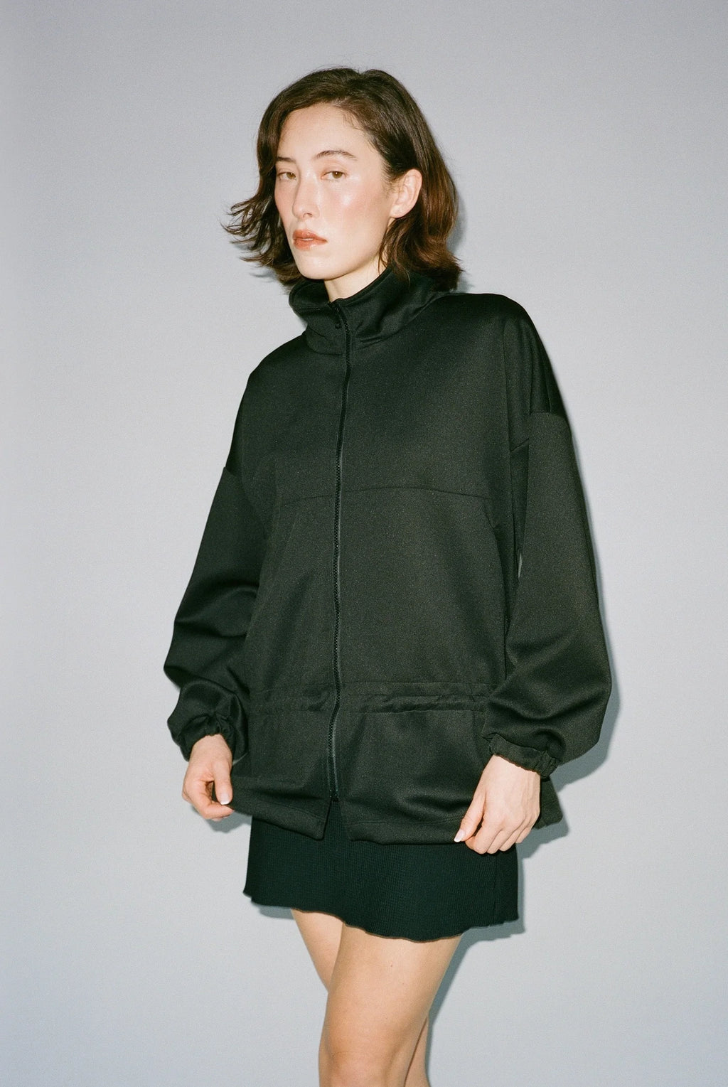 Woman wearing a black jacket and skirt against a gray background