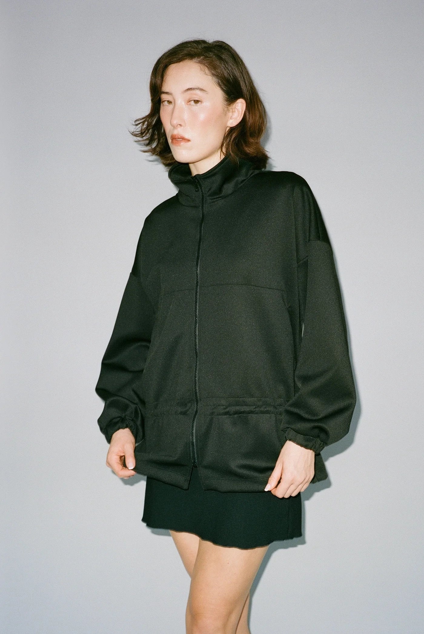 Woman wearing a black jacket and skirt against a gray background