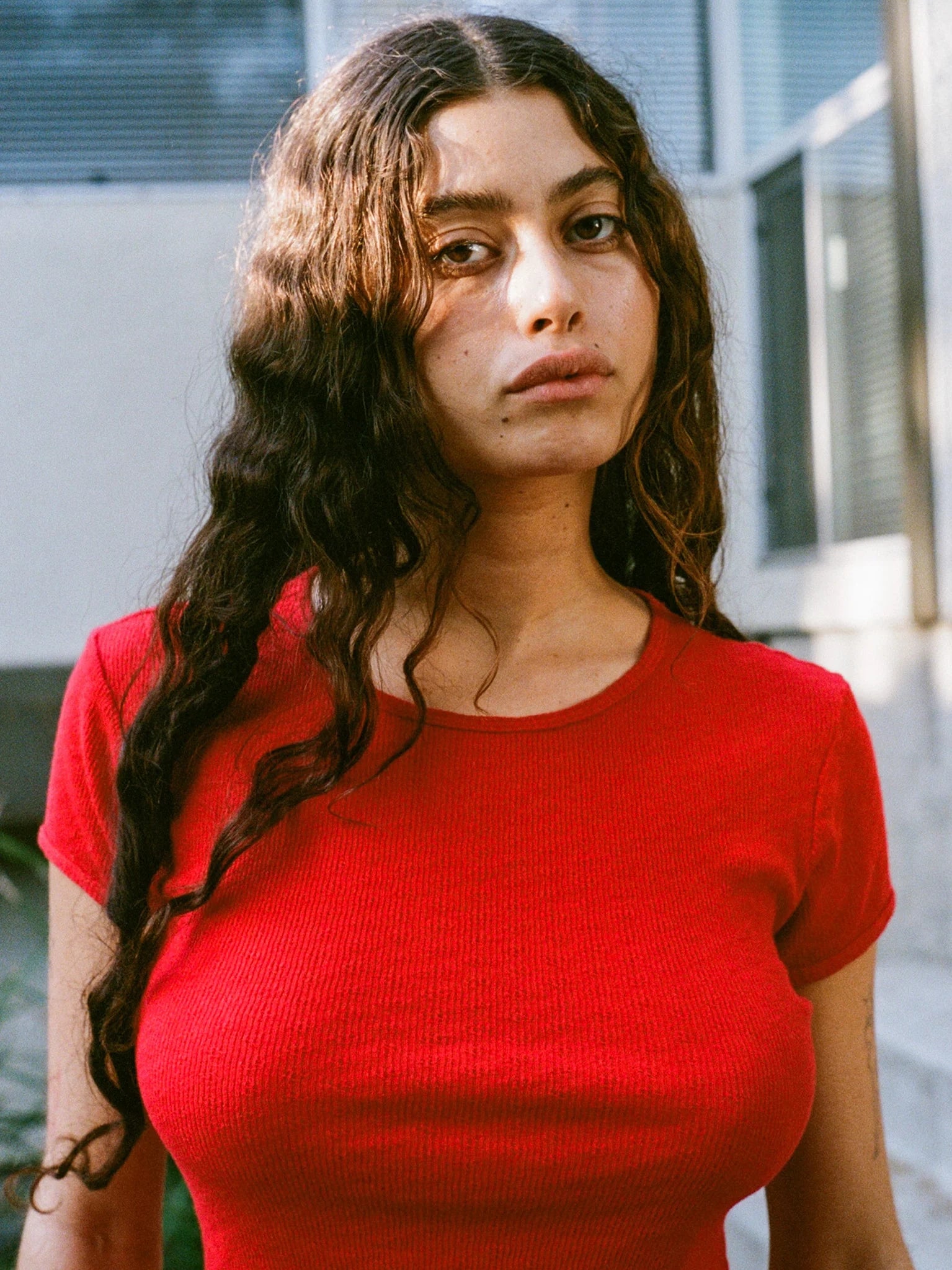 Woman wearing a red shirt with a blurred outdoor background