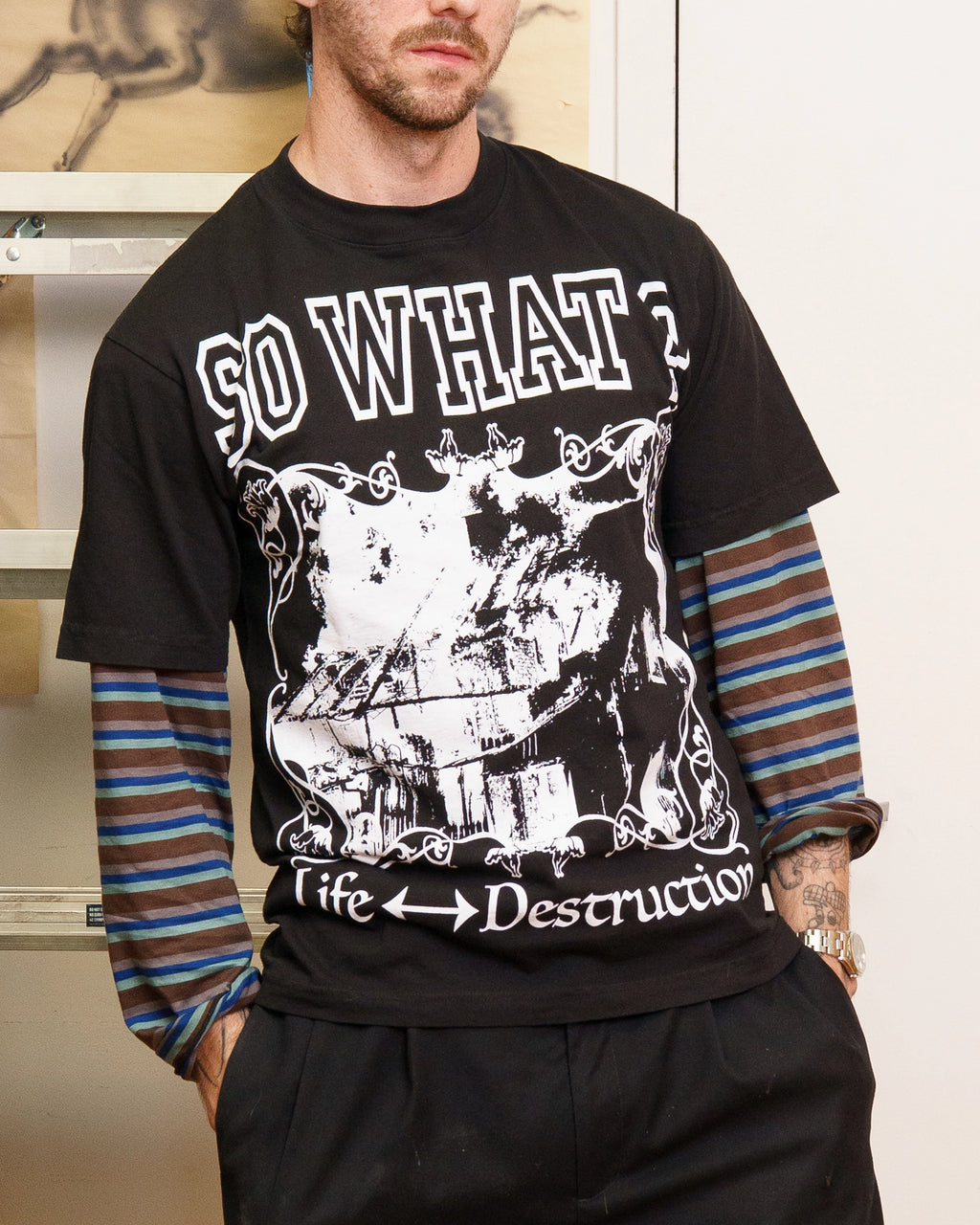 Model wearing black Henry Johnson graphic tee with oversized SO WHAT? typography, distressed artwork and Life ↔ Destruction lettering on the front.