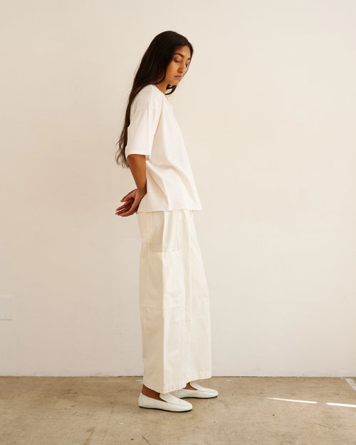 Side view of model wearing The Baggy Painter Crop in Ecru by Jamie Haller with a white oversized T-shirt.