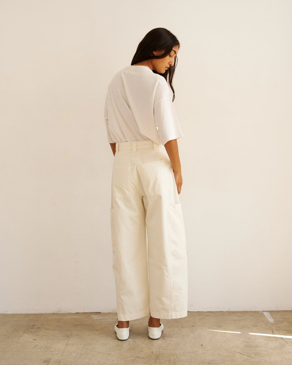 Back view of model wearing The Baggy Painter Crop in Ecru by Jamie Haller with a white oversized T-shirt.