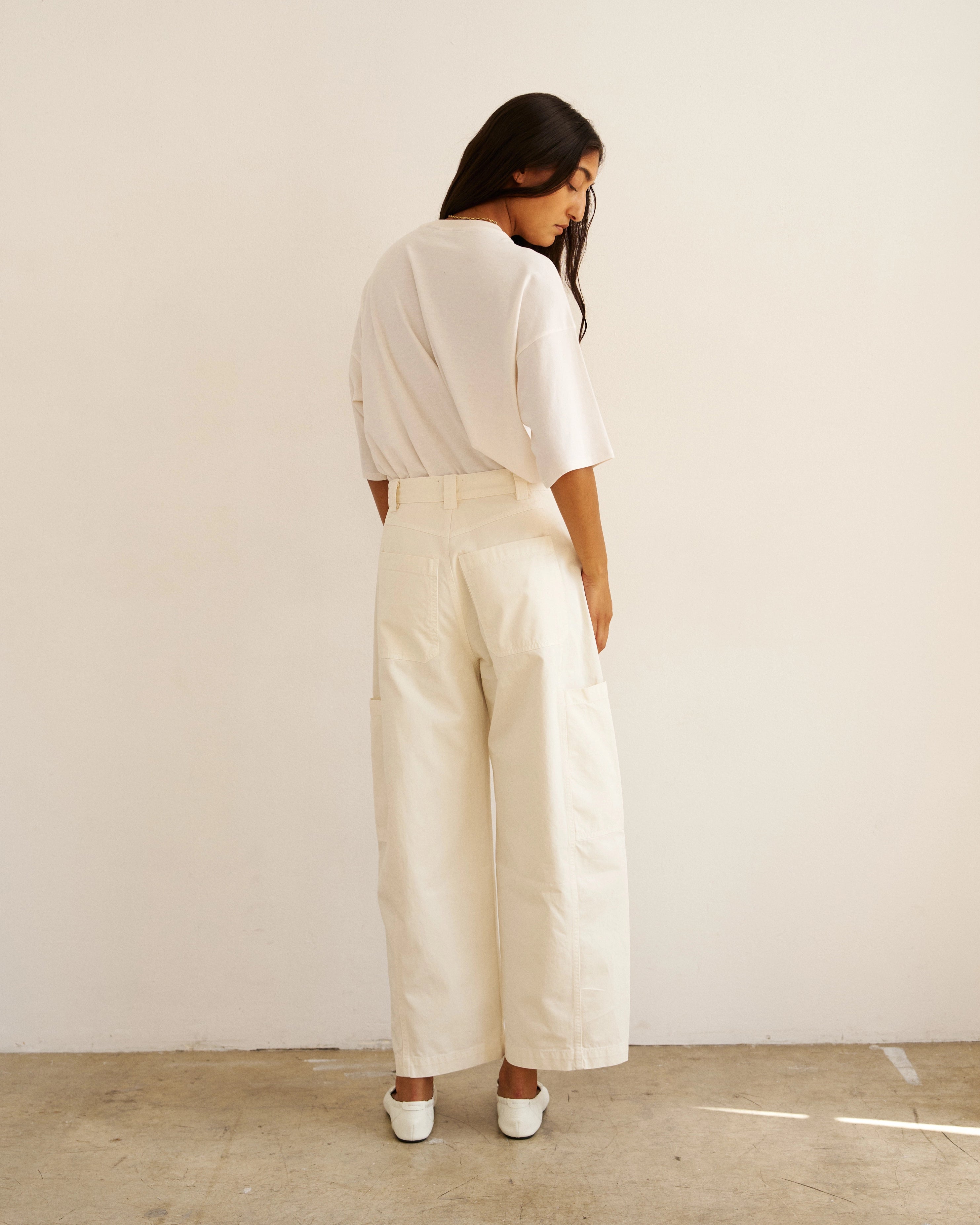 Back view of model wearing The Baggy Painter Crop in Ecru by Jamie Haller with a white oversized T-shirt.