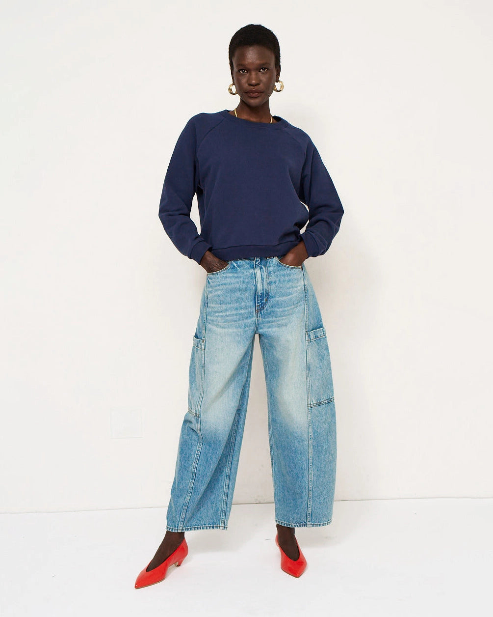 Model wearing Jamie Haller Crop Painter Jean in worn indigo with a baggy cropped silhouette and inset patch pockets.