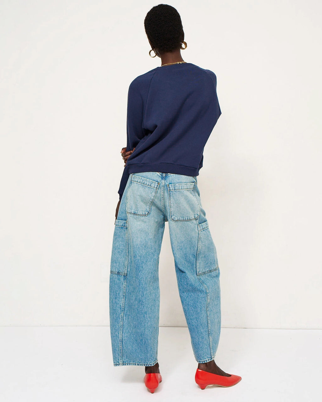 Model wearing Jamie Haller Crop Painter Jean in worn indigo with a baggy cropped silhouette and inset patch pockets.