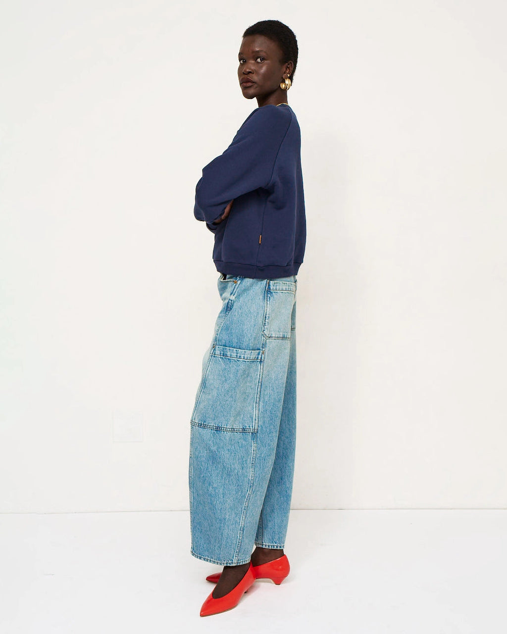Model wearing Jamie Haller Crop Painter Jean in worn indigo with a baggy cropped silhouette and inset patch pockets.