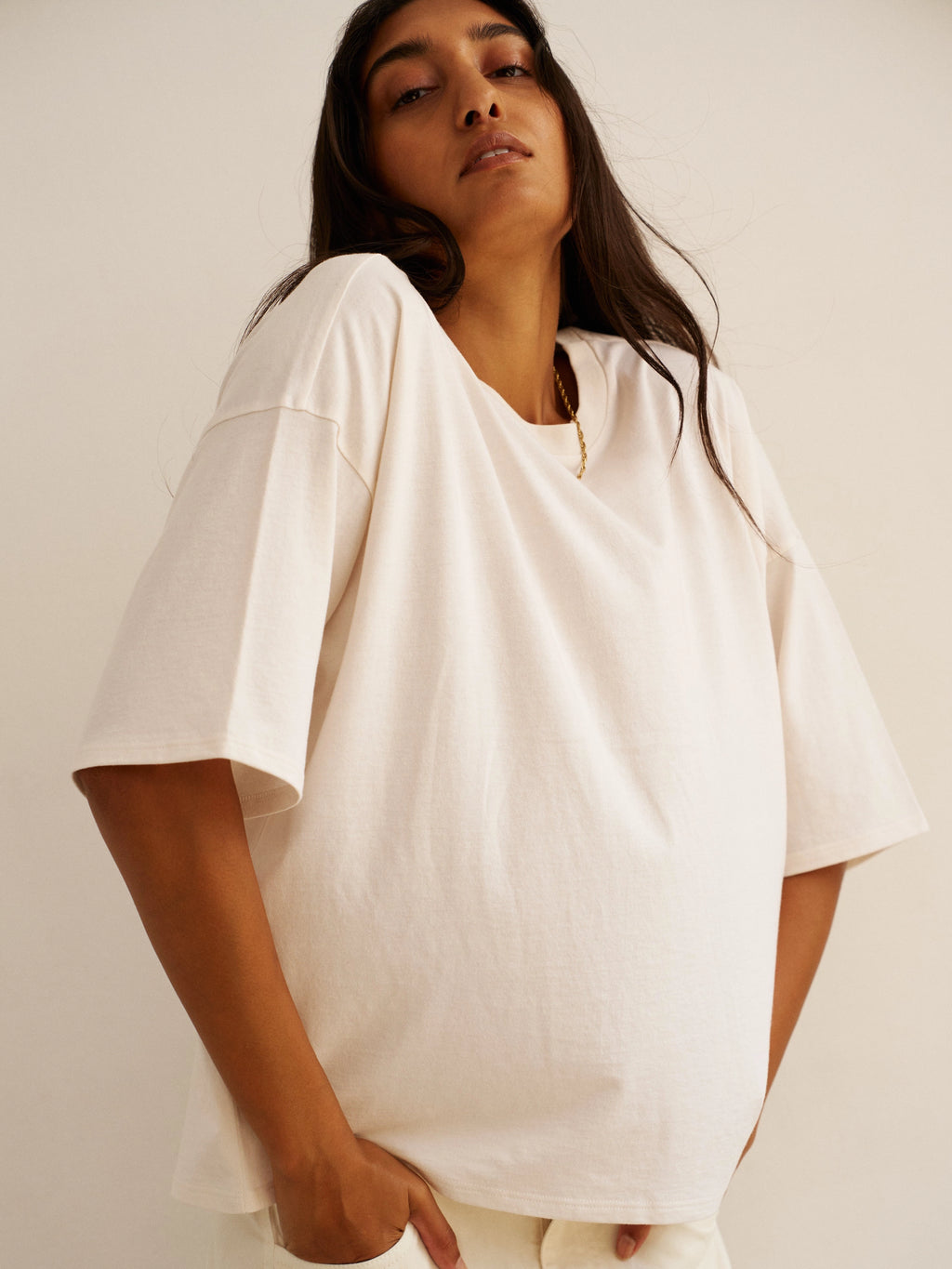 Woman wearing a white oversized shirt against a plain background