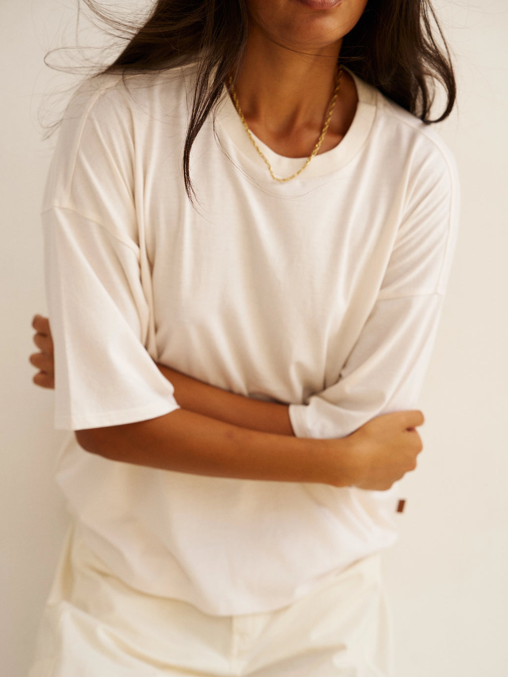 Person wearing a white t-shirt with a plain background