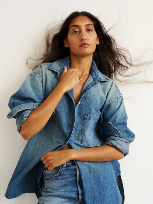 Woman wearing a denim shirt and jeans against a white background