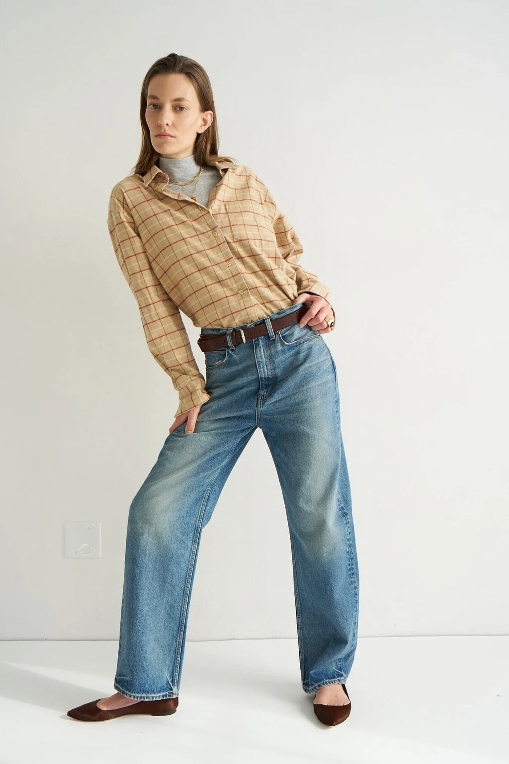 Person wearing a plaid shirt and jeans on a white background