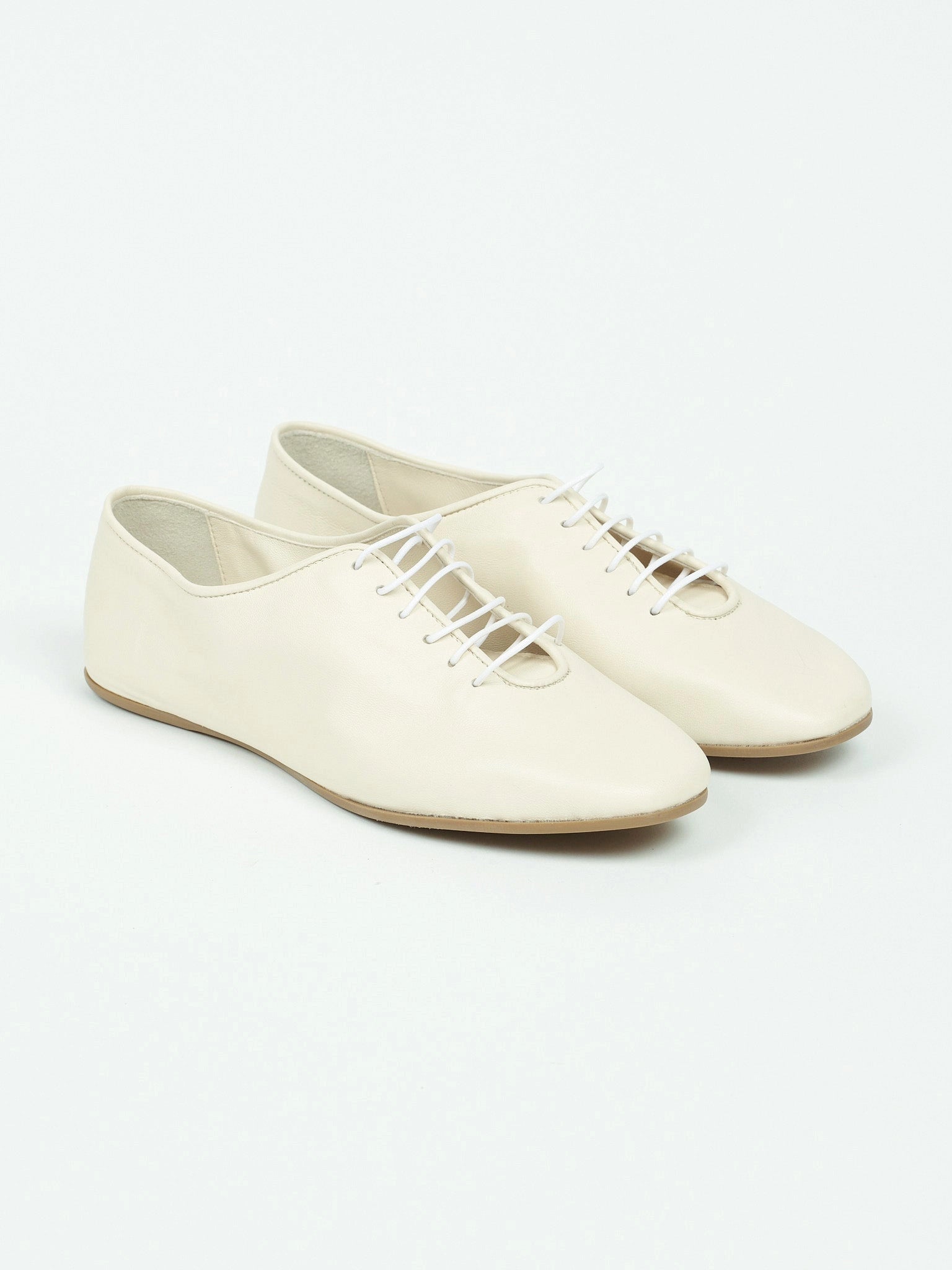 Pair of white lace-up shoes on a light gray background