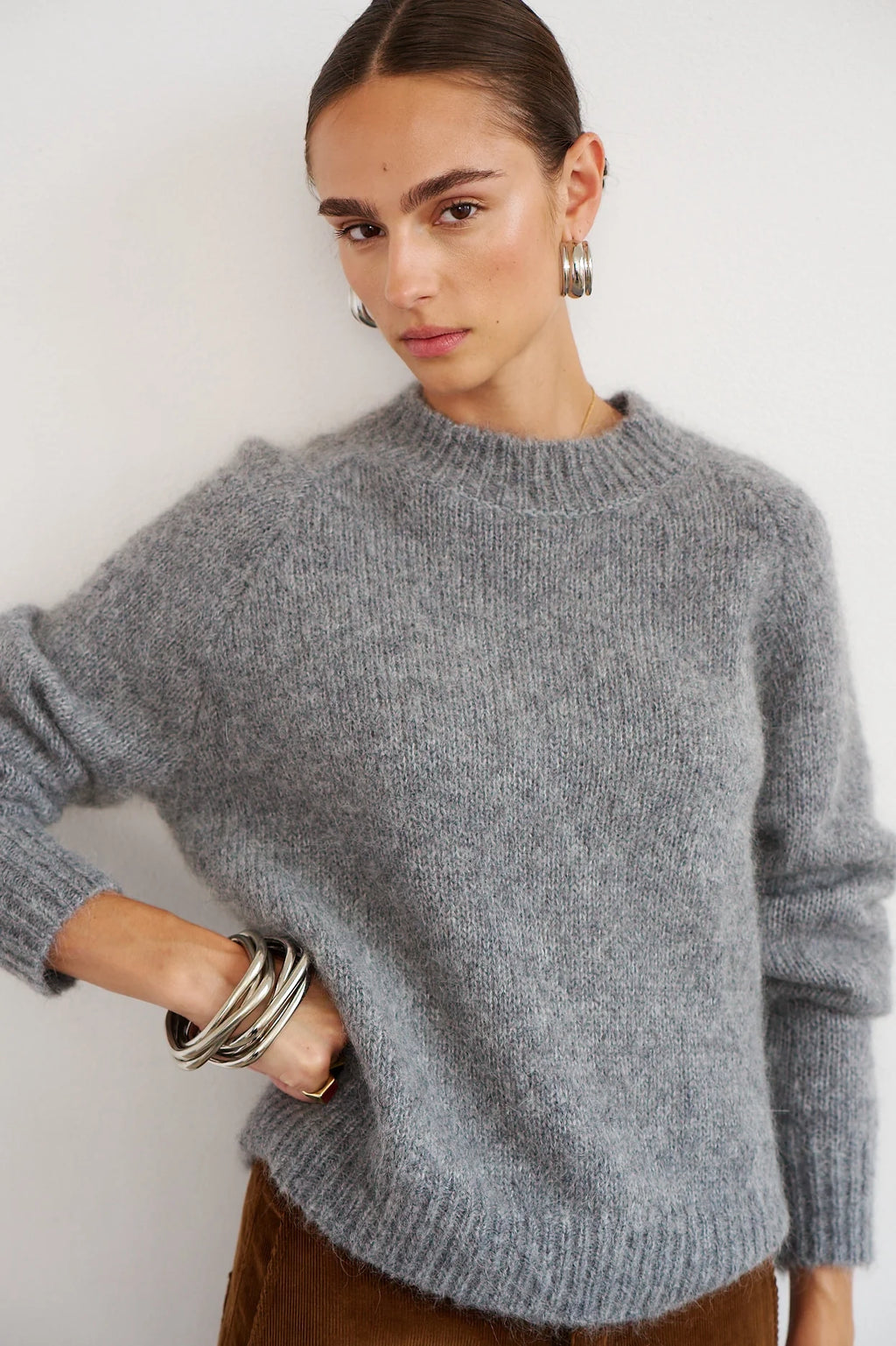 Woman wearing a gray sweater against a white background