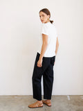 Person wearing a white t-shirt and black pants against a plain background