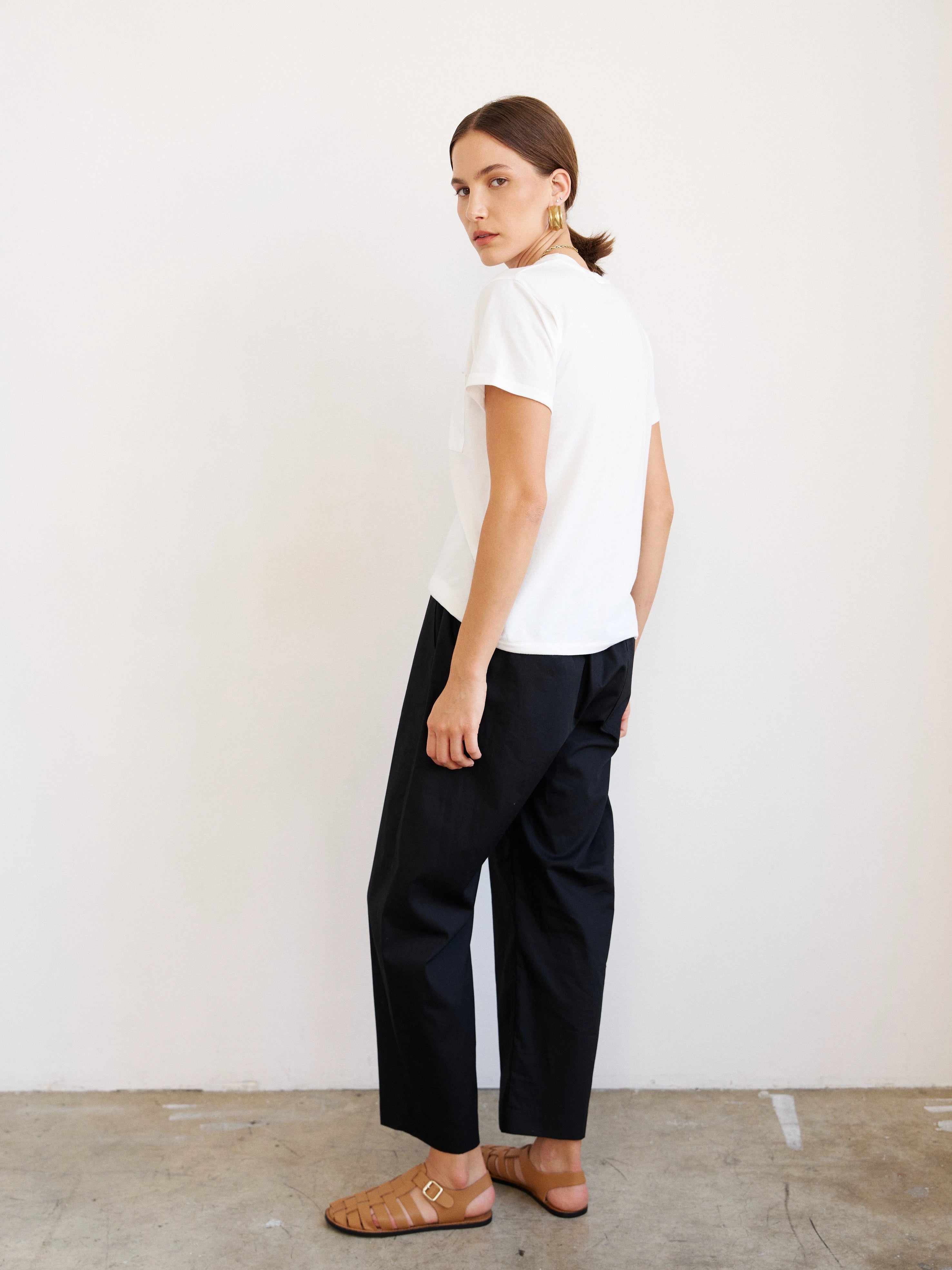 Person wearing a white t-shirt and black pants against a plain background