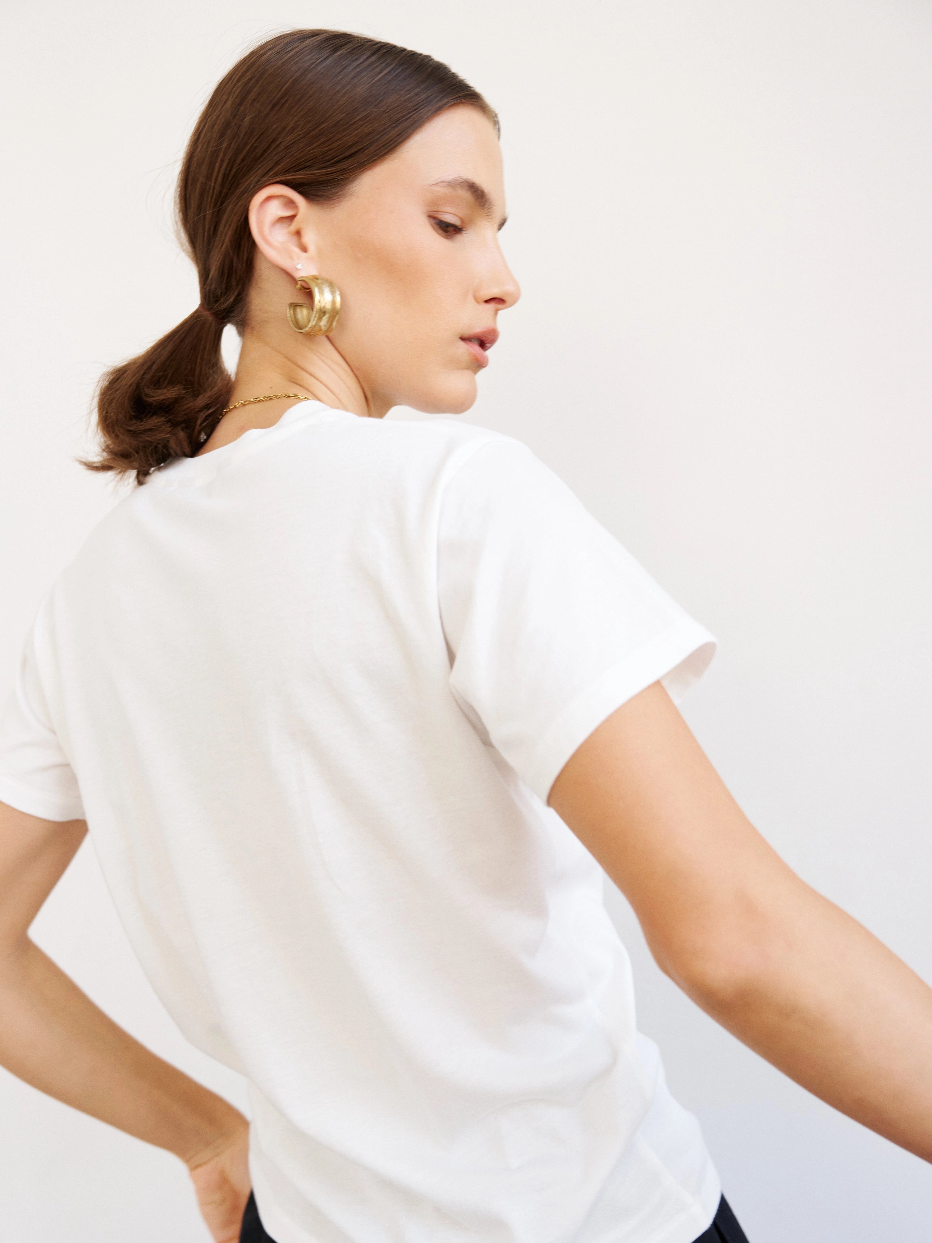 Woman wearing a white t-shirt against a plain background