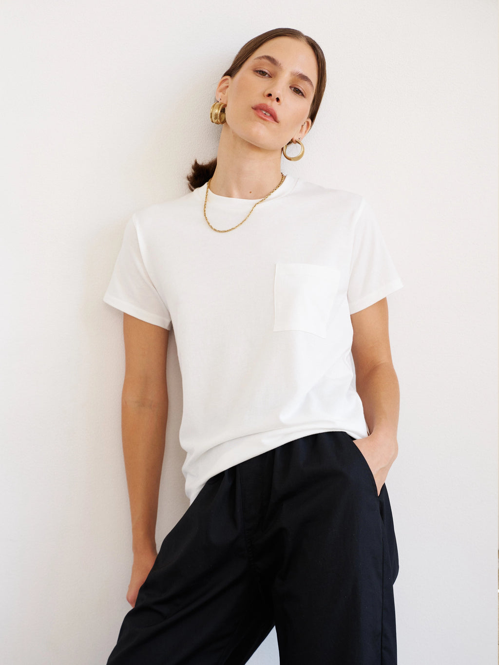 Woman wearing a white t-shirt and black pants against a white background