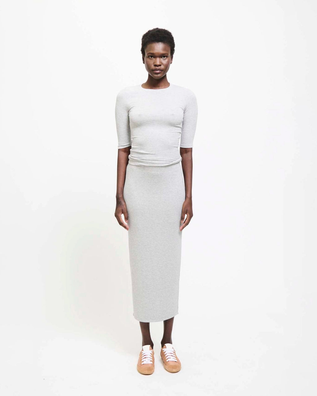 Model wearing Jamie Haller Rib Pencil Skirt in heather grey with a slim, straight silhouette and ankle-length hem.