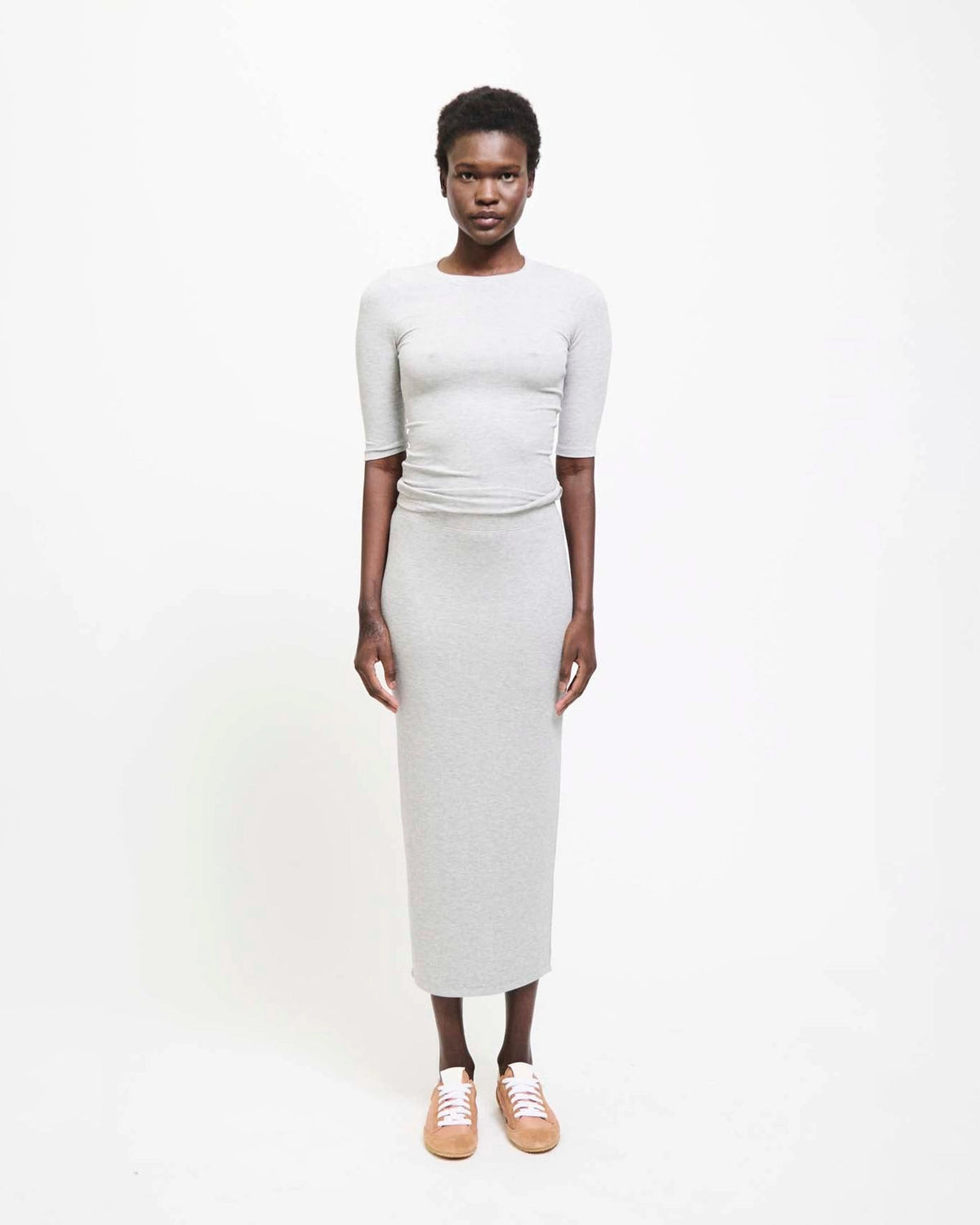 Model wearing Jamie Haller Rib Pencil Skirt in heather grey with a slim, straight silhouette and ankle-length hem.