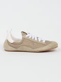 Beige sneaker with white laces on a light gray background