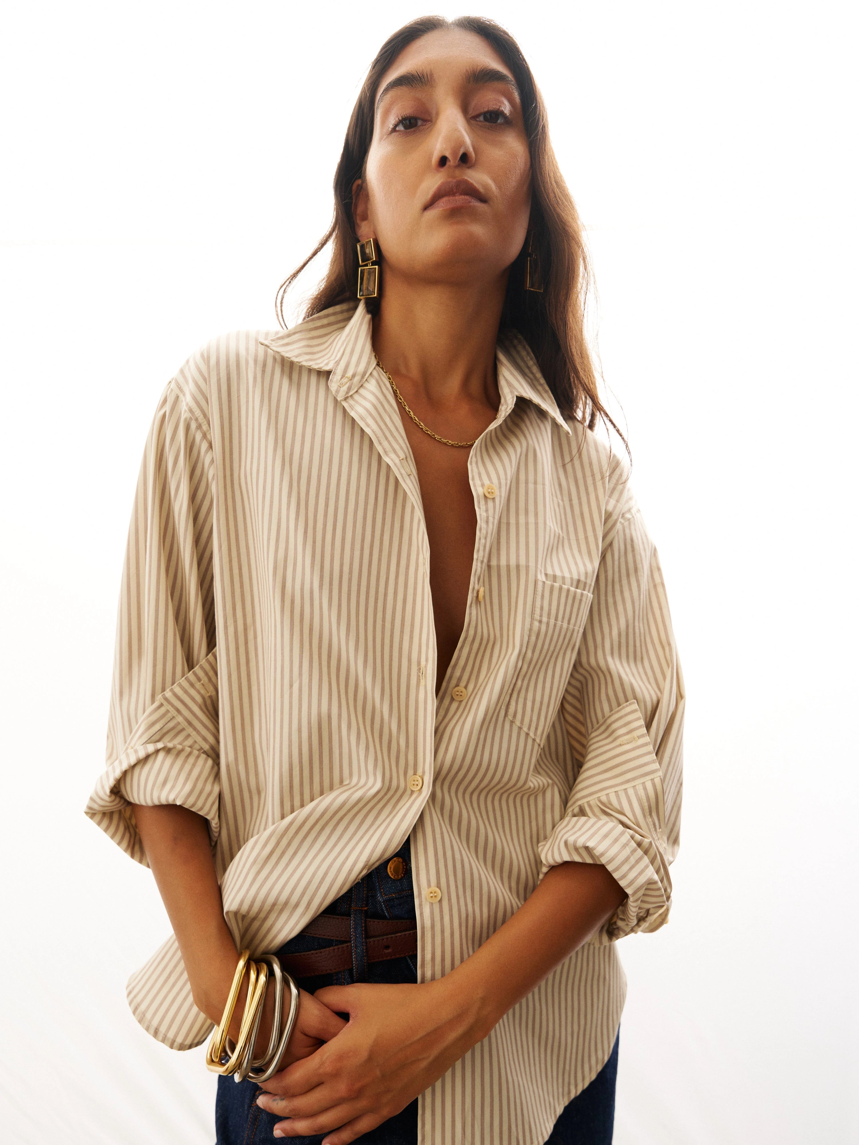 Woman wearing a striped shirt with rolled-up sleeves on a white background