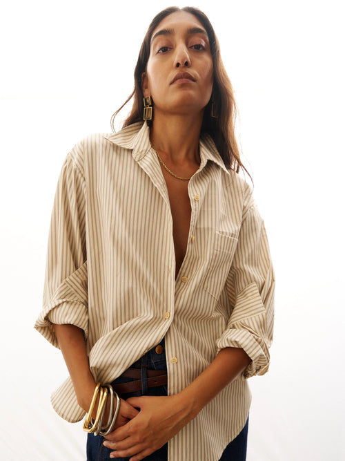 Woman wearing a striped shirt with rolled-up sleeves on a white background