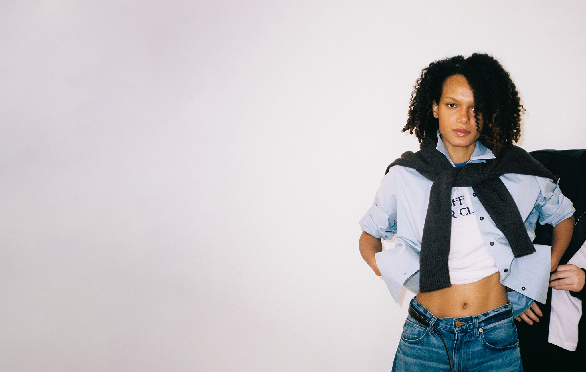 Person wearing a black scarf and cropped shirt with text on a plain background