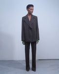 Model wearing NOMIA Double Breasted Jacket in earth with a structured silhouette, side slits and waist carabiner detail.