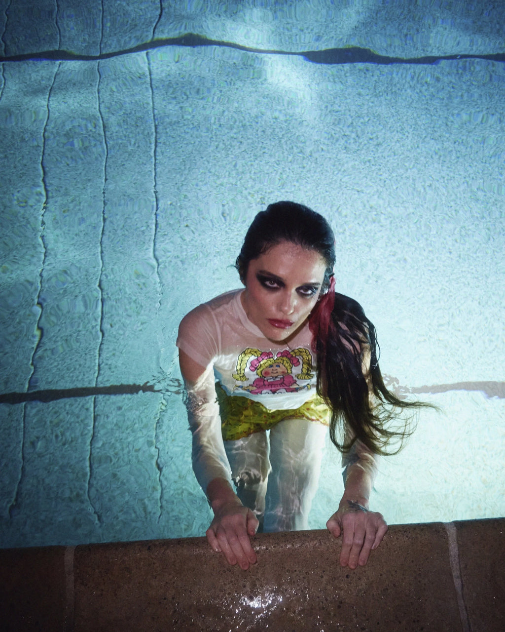 Sky Ferreira underwater with a textured pool wall background