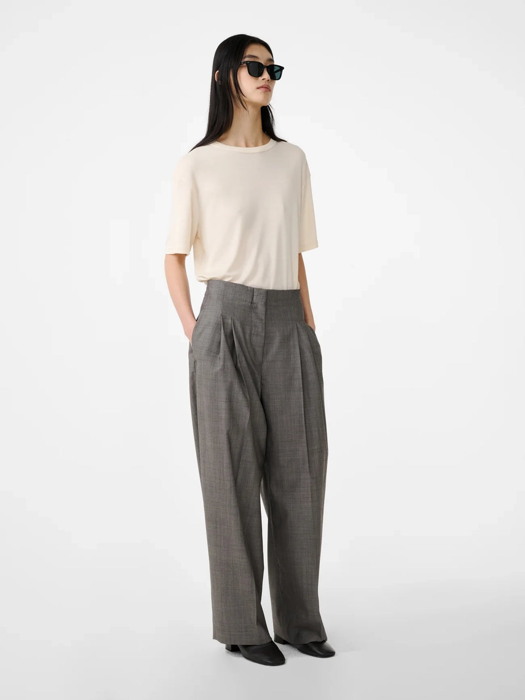 Woman wearing a white top and gray wide-leg pants on a white background