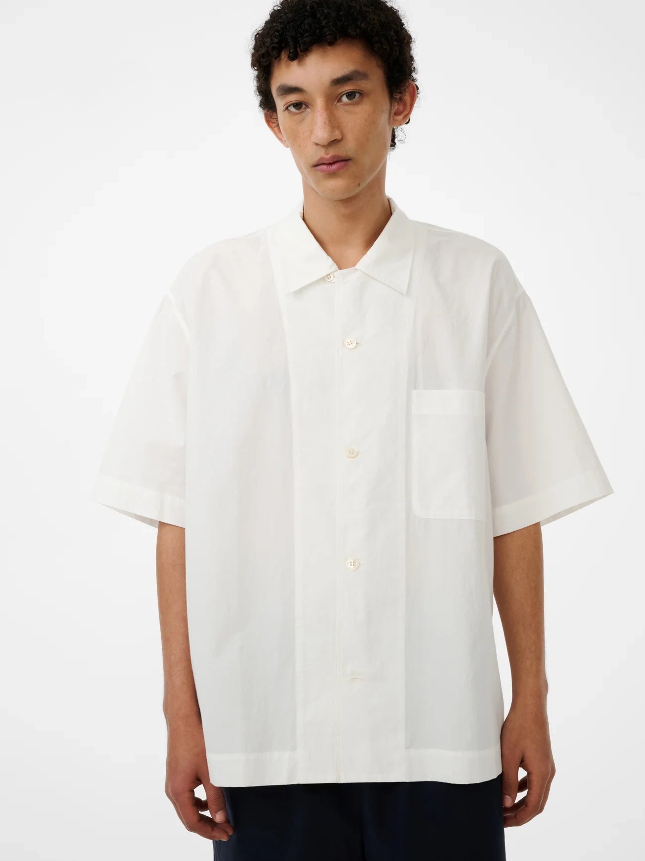 Person wearing a white short-sleeve shirt on a white background