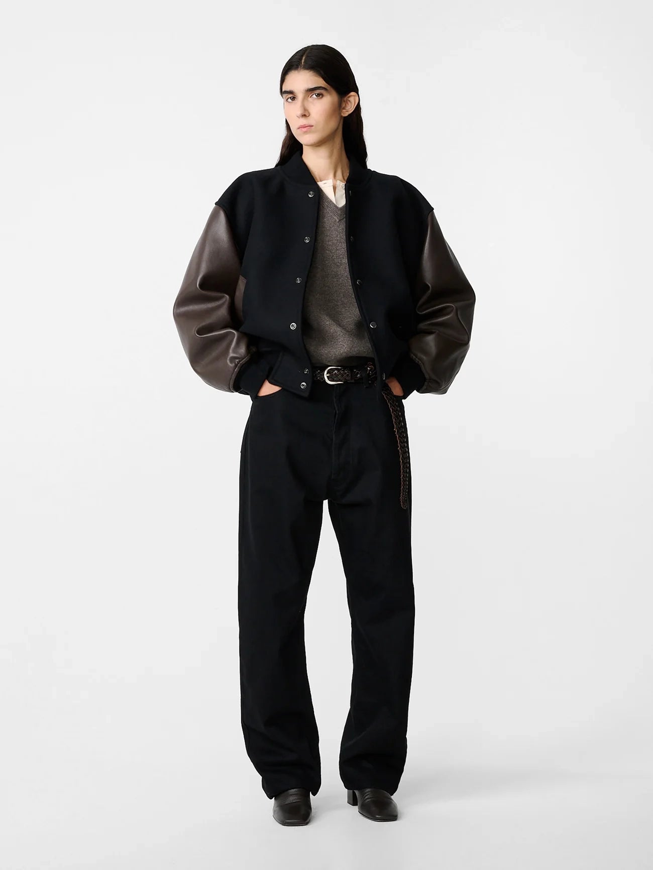 Person wearing a black and brown jacket with black pants on a white background